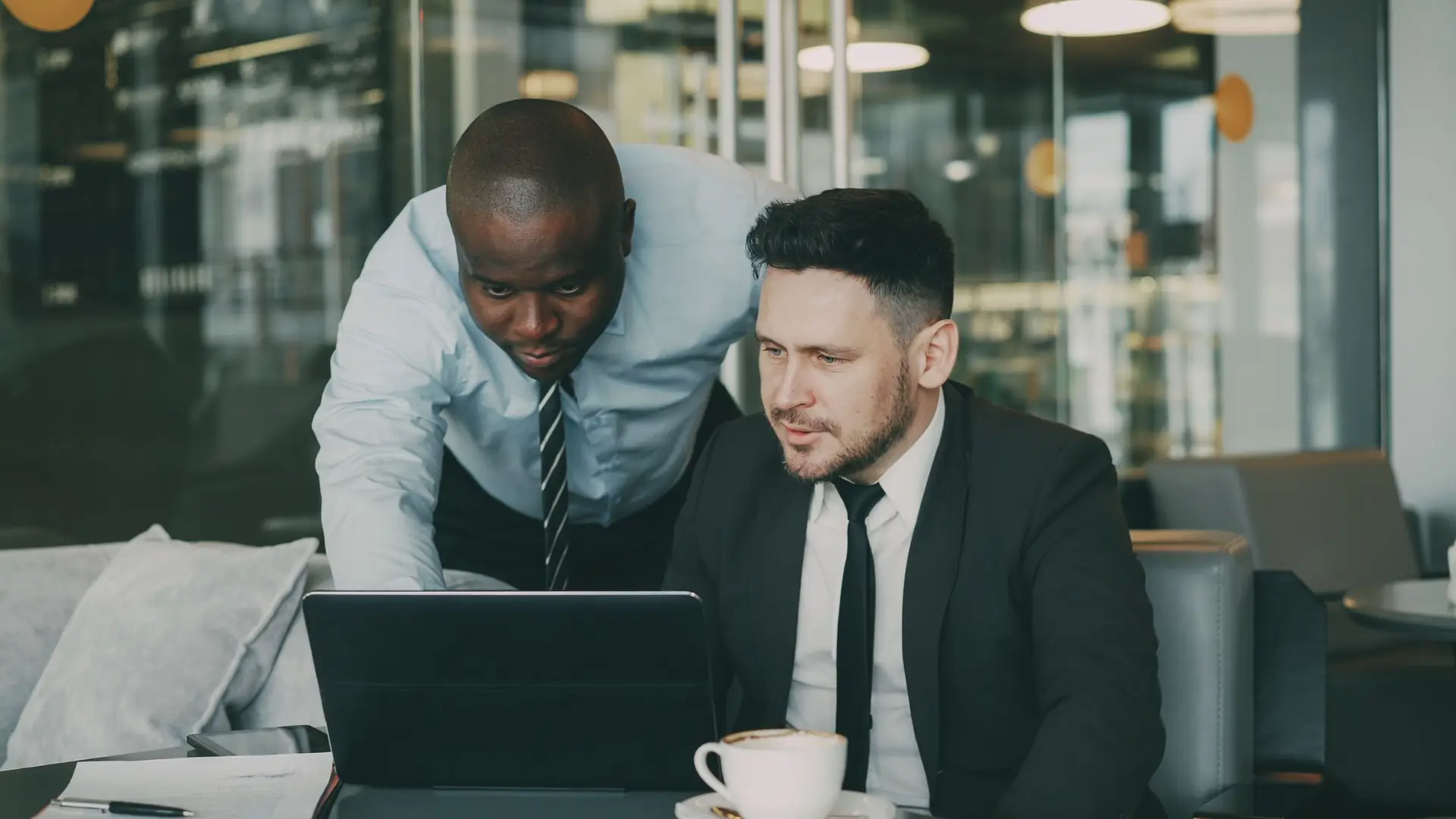 Zwei Fachpersonen prüfen gemeinsam Unterlagen auf einem Laptop